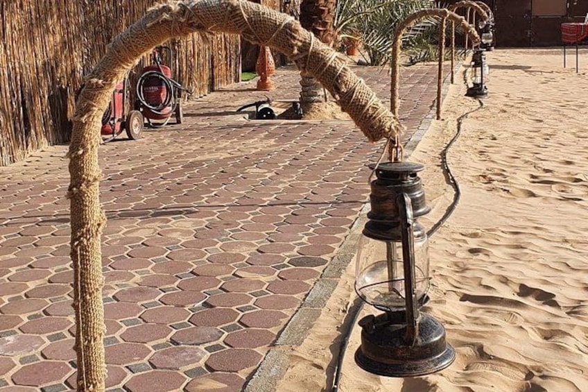 A rope archway leading to a lantern post on a paved pathway. 3