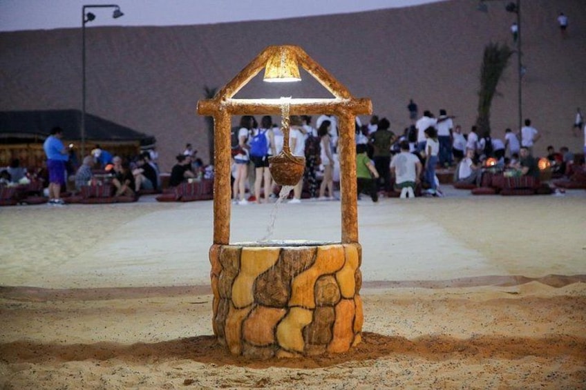 A stone structure with a roof and a hanging basket, surrounded by a crowd of people. 2