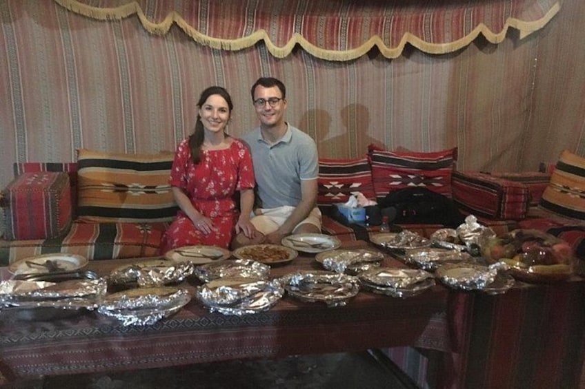 Un couple est assis à une table, devant des plats, et on aperçoit un canapé à motifs en arrière-plan. 3
