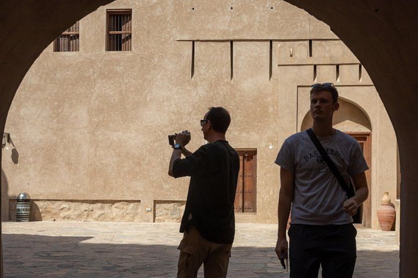 Dos personas en un arco, una tomando una foto, y un edificio con una puerta y ventanas al fondo. 5