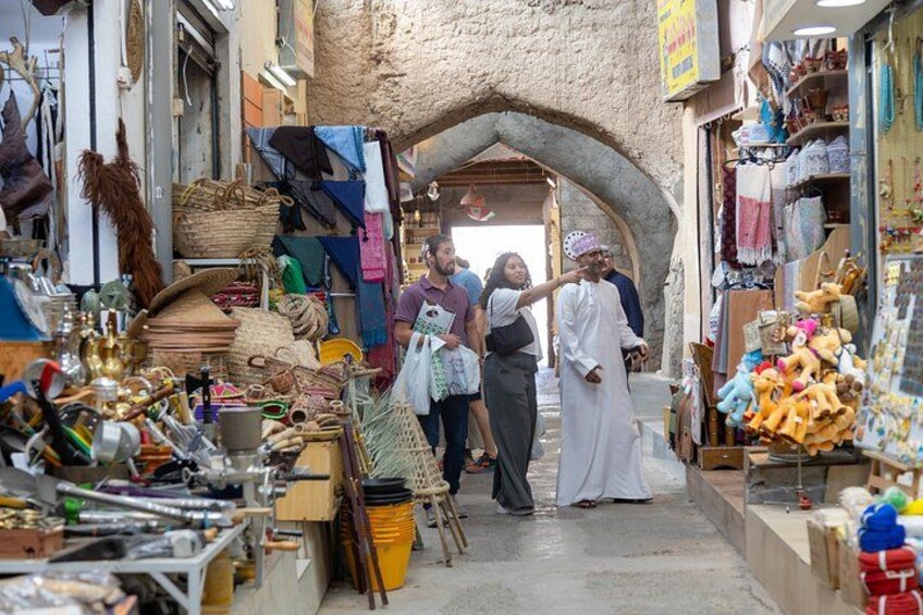 Une rue étroite bordée d’étals où sont vendus divers articles, comme des sacs, des jouets et des articles ménagers. 4