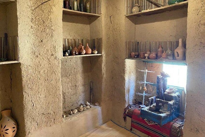 Una habitación rústica con estantes que exhiben cerámica y un tendedero con objetos colgando. 5