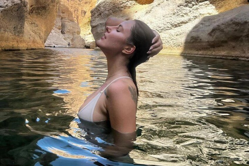 A person in a natural water body surrounded by rocky terrain. 1