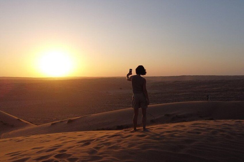 Una persona fotografiando la puesta de sol sobre un paisaje desértico. 2