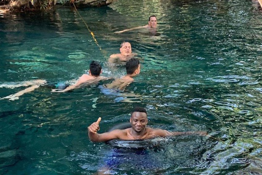 Personas nadando en una masa de agua clara y natural rodeada de rocas. 1