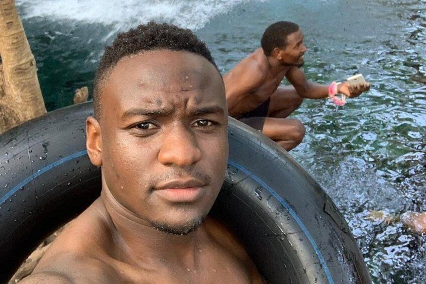 Una persona dentro de un flotador inflable negro en el agua, con otra persona al fondo. 4