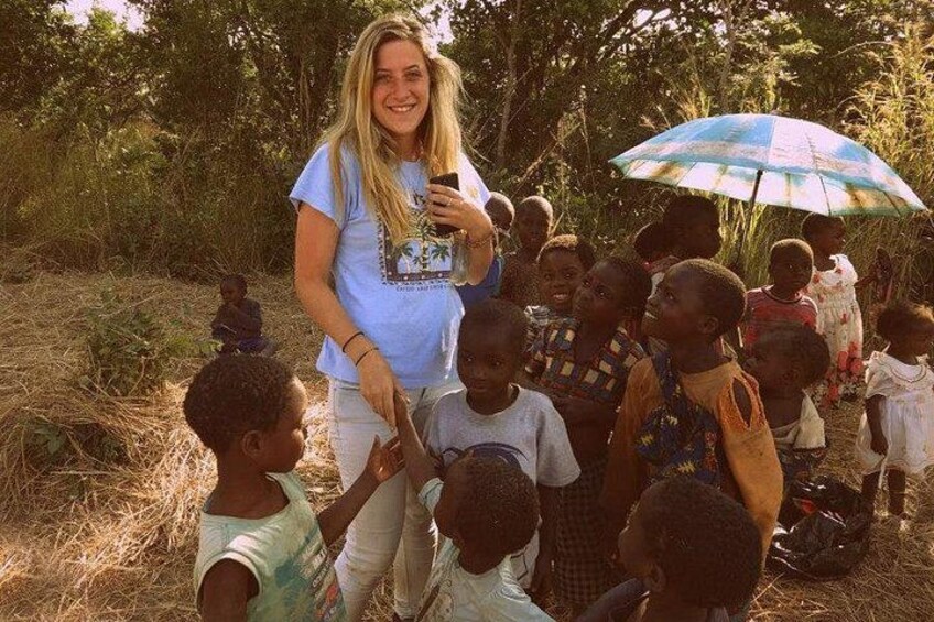 A woman with a smartphone, a group of children, and a colorful umbrella in a natural setting. 2
