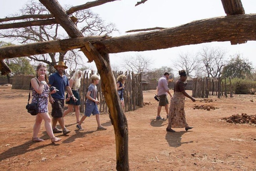 A group of people walking in a dry, open area with sparse vegetation and a wooden fence. 5