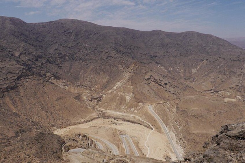 Een ruig berglandschap met een kronkelende onverharde weg. 1