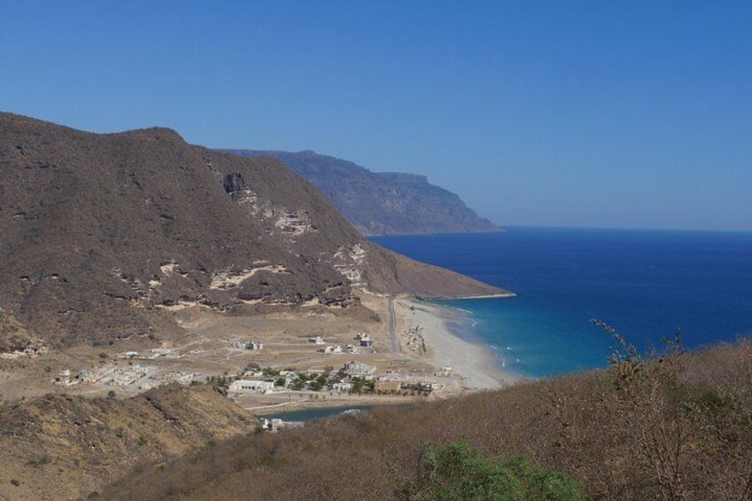 Een kustlandschap met een strand, een klein dorpje en een berg op de achtergrond. 4