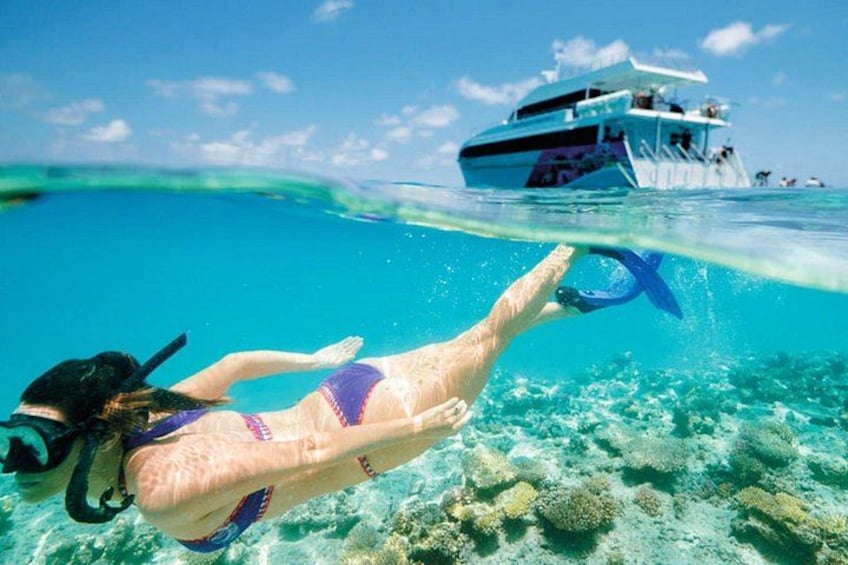 Iemand snorkelt onderwater, met een boot op de achtergrond. 1
