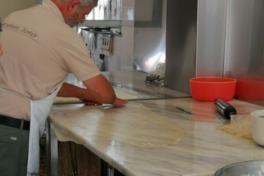 A person rolling dough on a marble countertop in a kitchen. 3