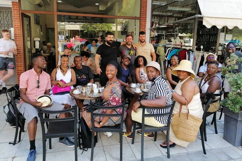 A group of people sitting at tables outdoors, engaged in conversation. 3