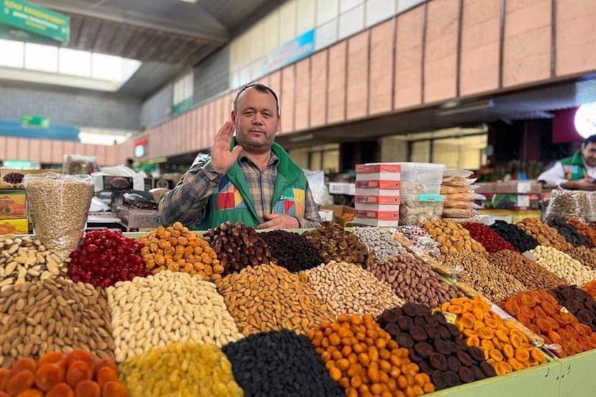 En person står bakom ett bord med olika sorters nötter och torkad frukt. 3