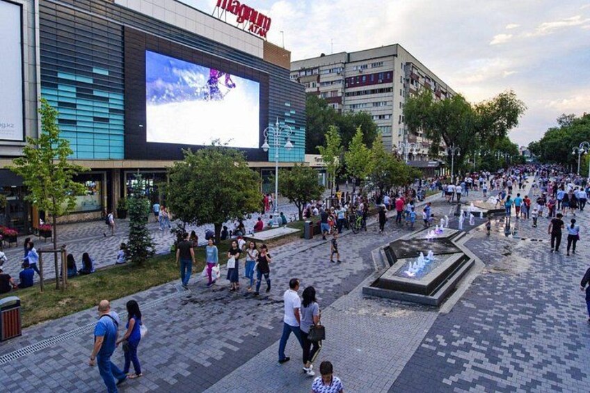 A public square with a large digital billboard, a fountain, and people walking around. 2