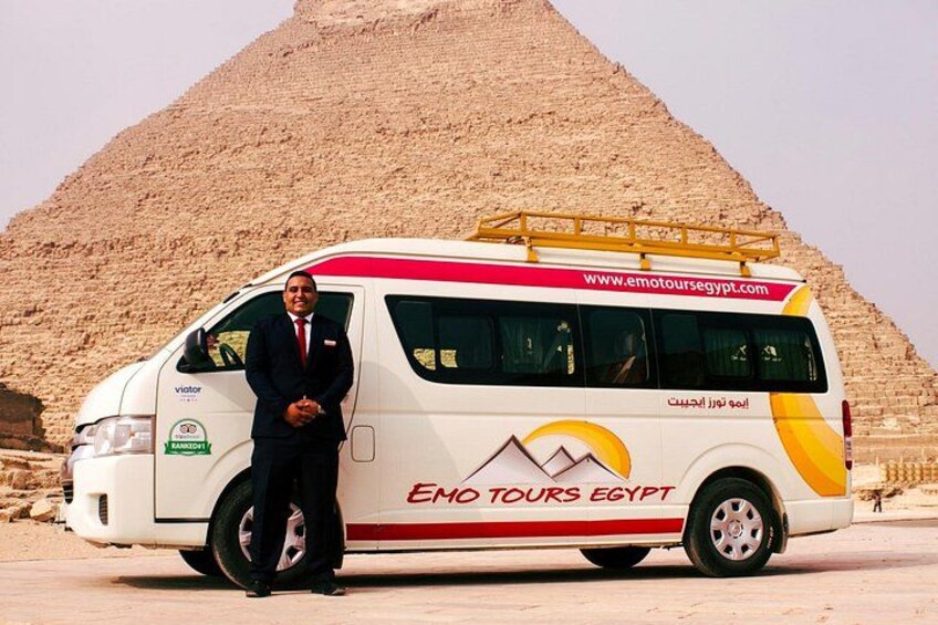 A tour bus with 'Em Tours Egypt' branding parked in front of a pyramid. 2