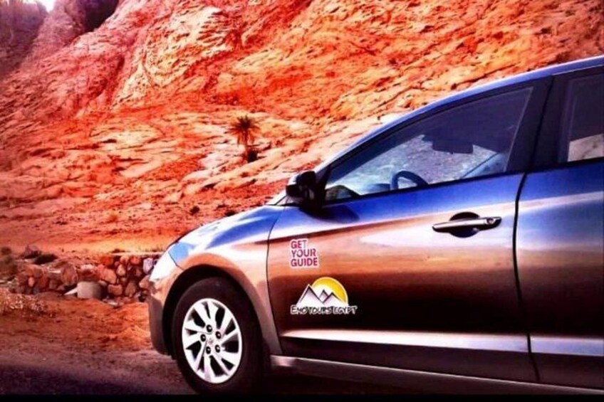 Un coche aparcado en un desierto con un fondo rocoso. 4