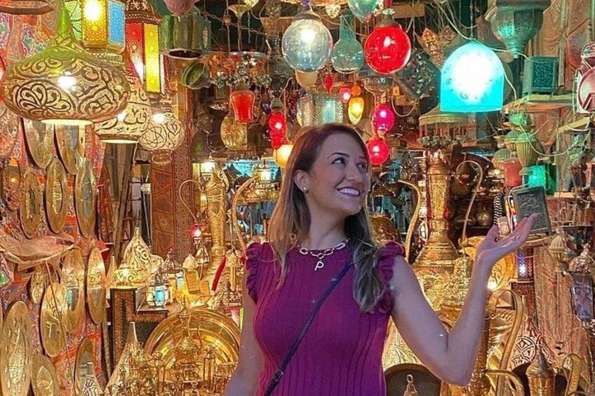 A person in a purple dress amidst a variety of ornate, colorful glassware and decorative items. 2