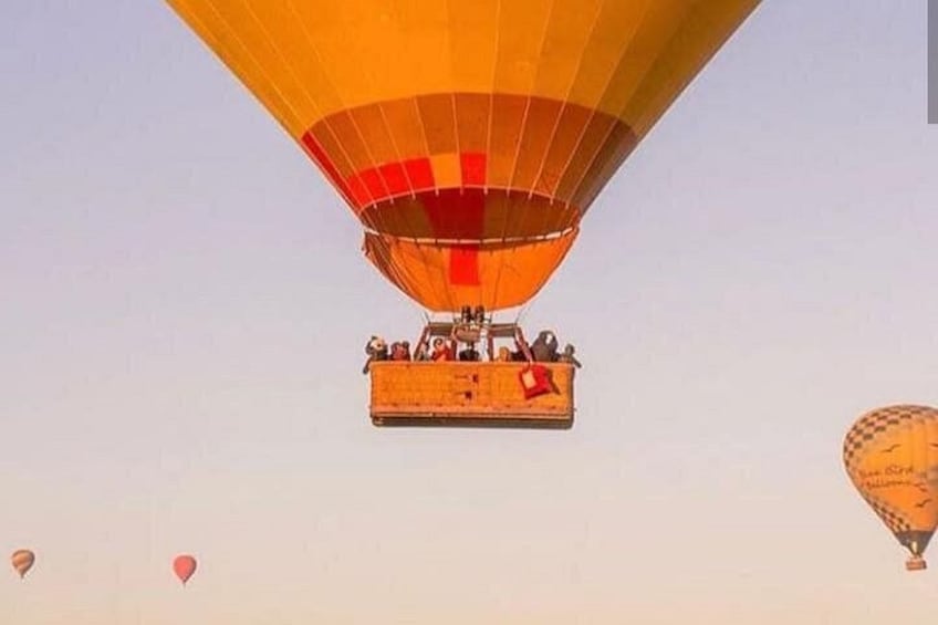 Un globo aerostático con pasajeros, otro globo al fondo y un cielo despejado. 5