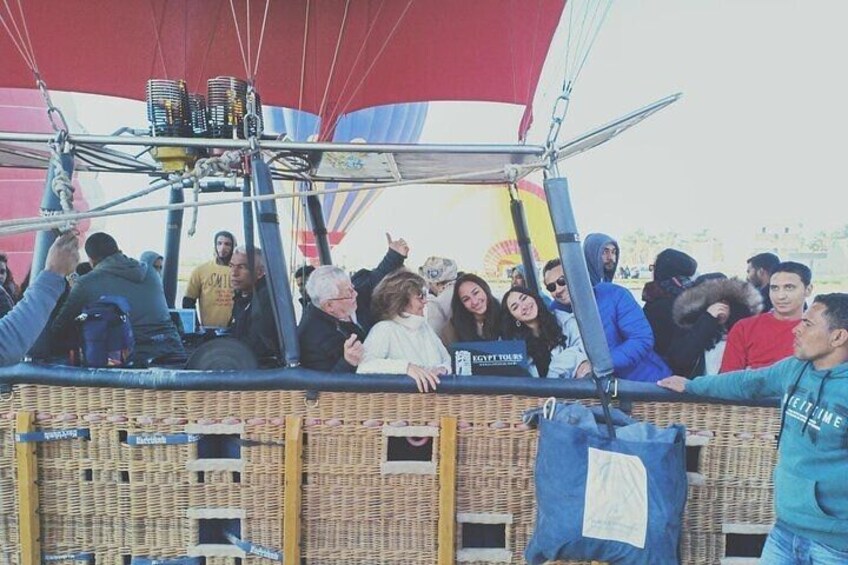 A hot air balloon with passengers, wicker baskets, and a red canopy. 2