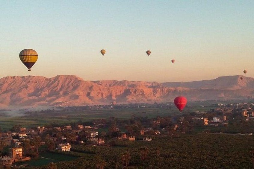 Un paisaje con montañas y globos aerostáticos en el cielo. 3
