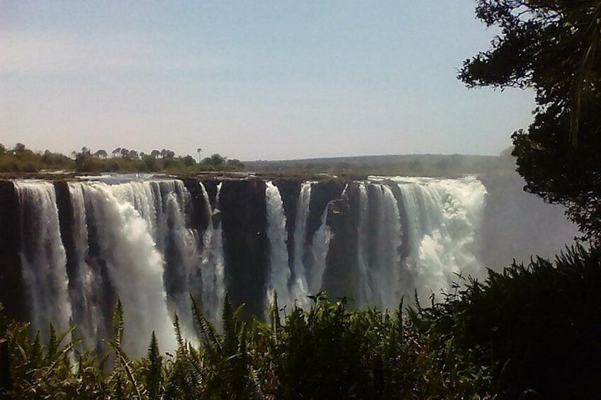 Een grote waterval met meerdere watervalbanen, omgeven door weelderige begroeiing. 1