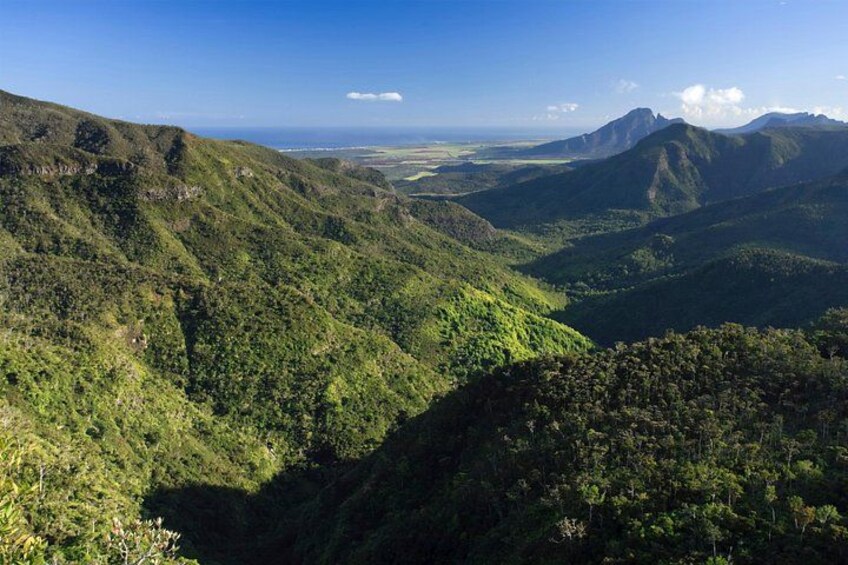 A mountainous landscape with dense green vegetation and a clear sky. 2