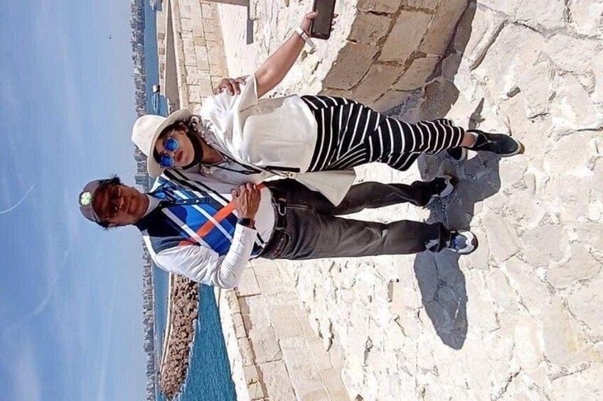 Dos personas de pie sobre un sendero de piedra junto al mar. 5