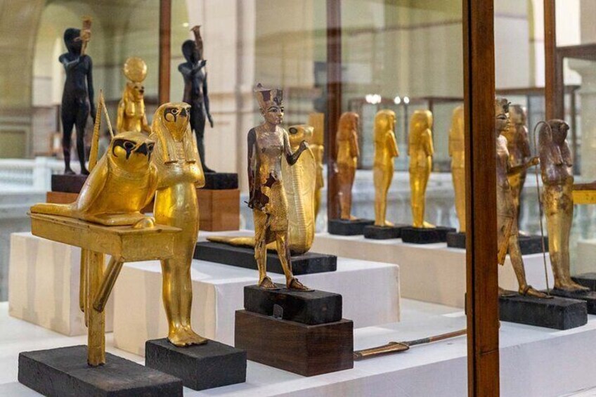 Gyllene egyptiska statyer visas på ett museum. 4