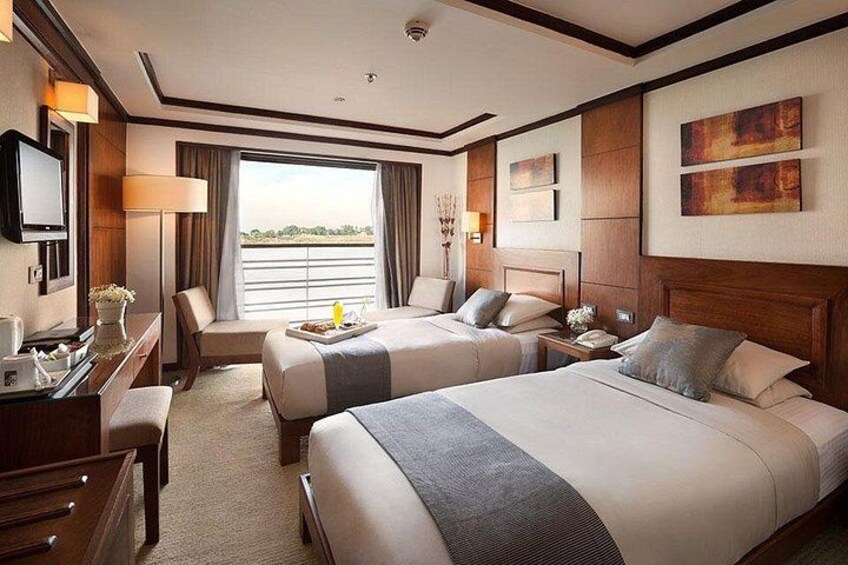 A hotel room with two beds, a desk, a chair, and a view of the outdoors. 4