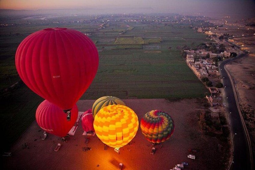 Hot air balloons over a rural landscape with fields and a road. 2