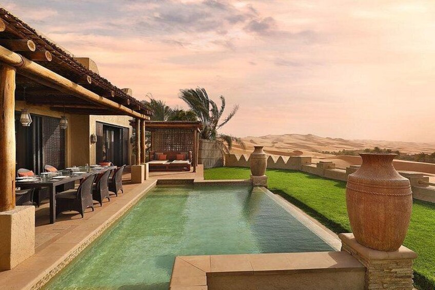 Une piscine avec un patio, un grand vase et un paysage désertique en arrière-plan. 2