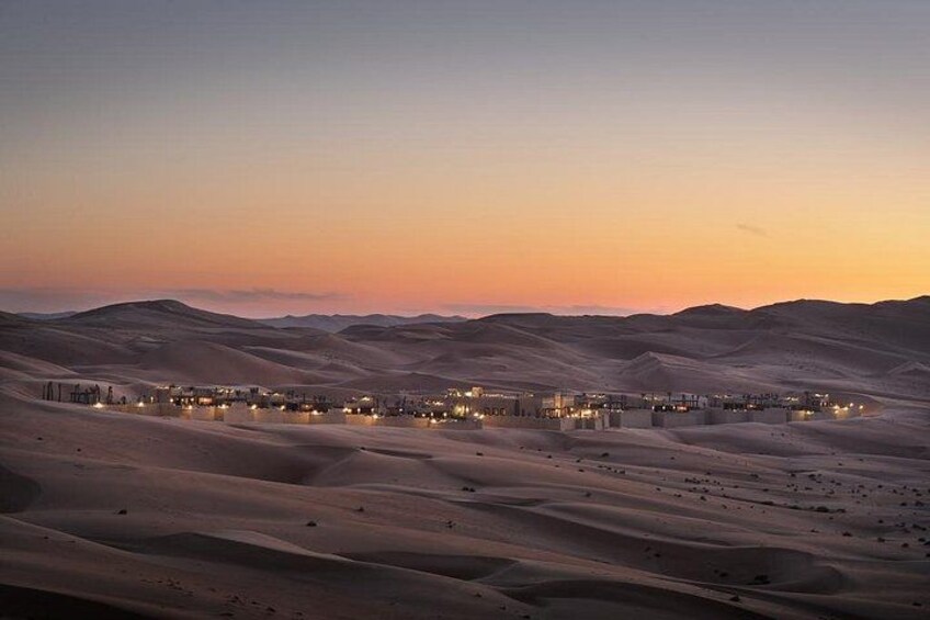 Un paysage désertique au crépuscule, avec un ensemble de bâtiments et des lumières. 3