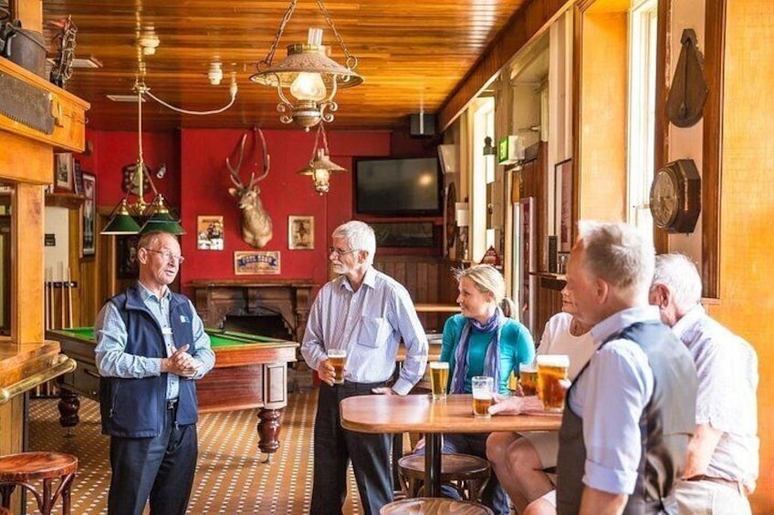 A group of people in a pub with wooden interiors, a billiards table, and a television. 2