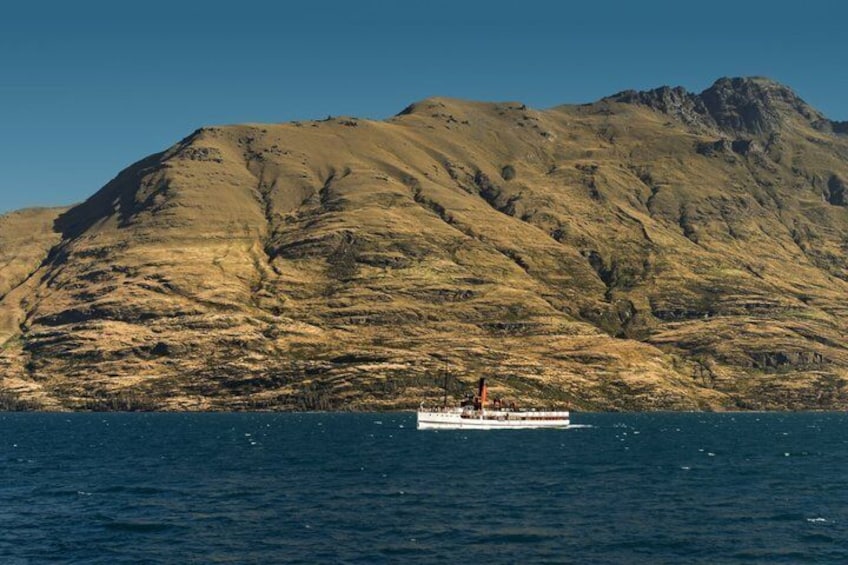 Ein Boot auf ruhigem Wasser, im Hintergrund eine gebirgige Landschaft. 5