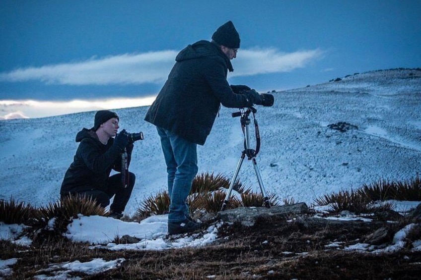 Two people with cameras on a snowy hill. 5