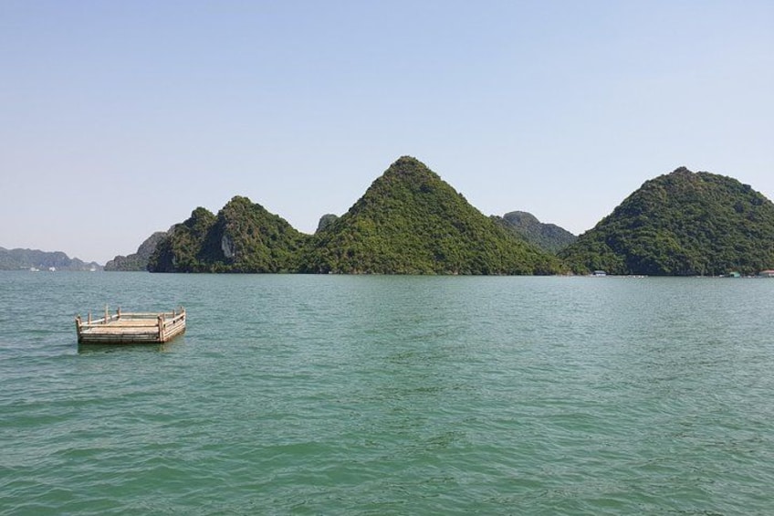 A calm body of water with a small wooden boat and lush green hills in the background. 2