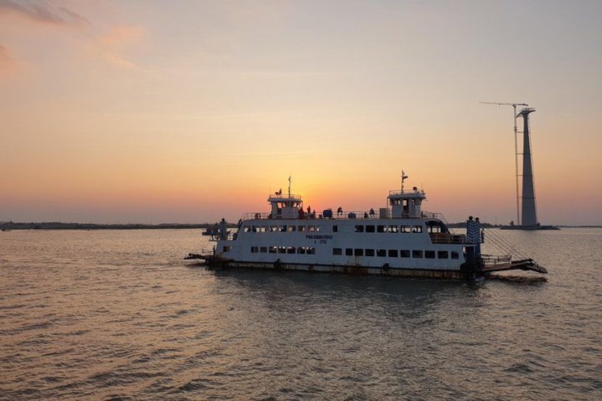 A ferry at sunset with a tower in the background. 3