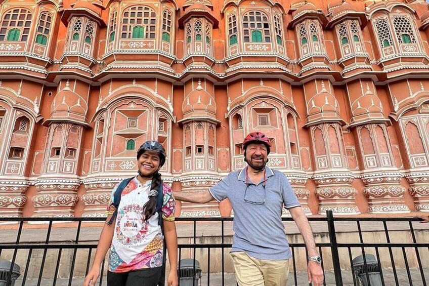 Two people standing in front of a large, ornate building with intricate architectural details. 2