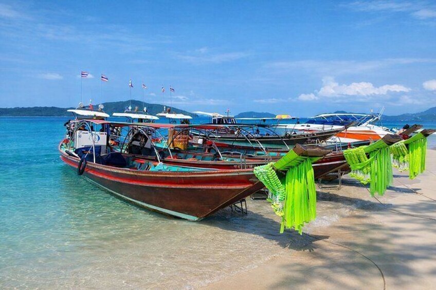 Una hilera de barcos amarrados en una playa con aguas cristalinas y montañas al fondo. 4