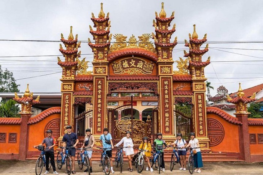 L’entrée d’un temple, ornée de décorations dorées élaborées, et un groupe de personnes à vélo. 2