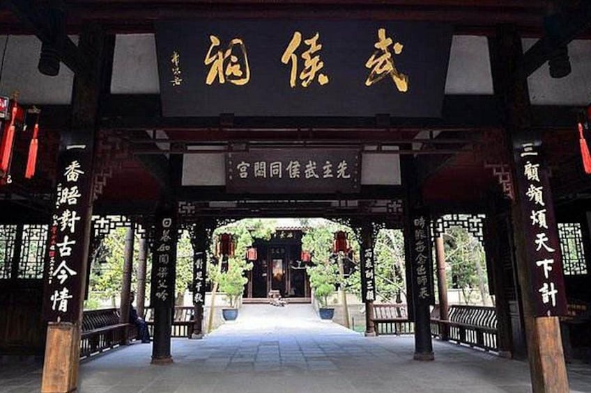 Ein traditionelles chinesisches Tor mit goldener Inschrift, einem mit Fliesen ausgelegten Weg und einem symmetrischen Aufbau. 4