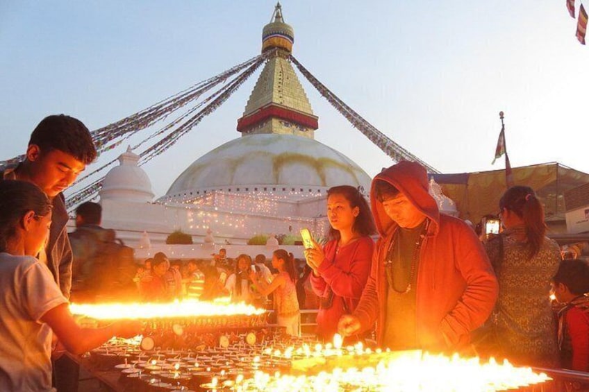 A group of people around a fire, with a large white building with a golden spire in the background. 1