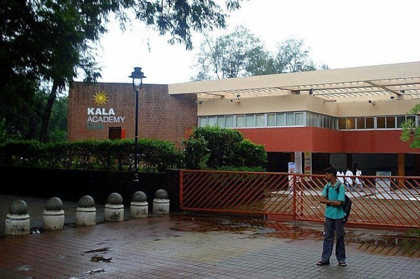 A building with a sign reading 'KALA ACADEMY' and a person standing near a red gate. 5