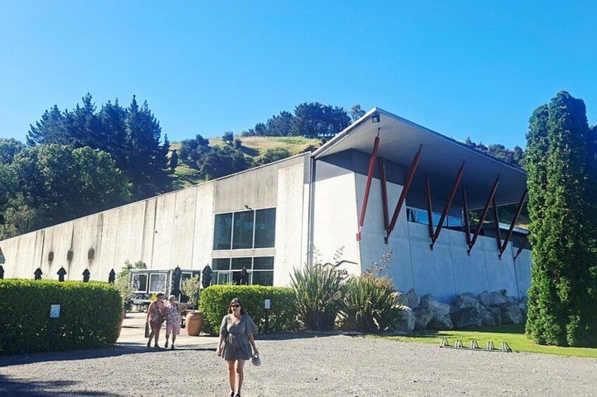 Un edificio moderno con techo inclinado y amplias ventanas, rodeado de setos cuidados y un camino de entrada de grava. 3