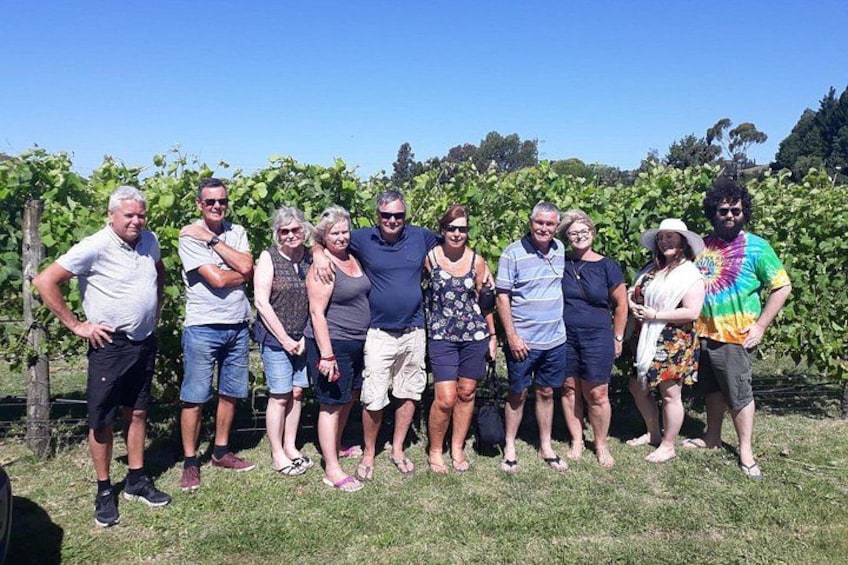 Eine Gruppe von Menschen steht draußen vor einem Weinberg. 4