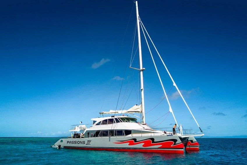 Un yacht blanc et rouge, baptisé PASSIONS 77, navigue sur des eaux d’un bleu limpide. 1
