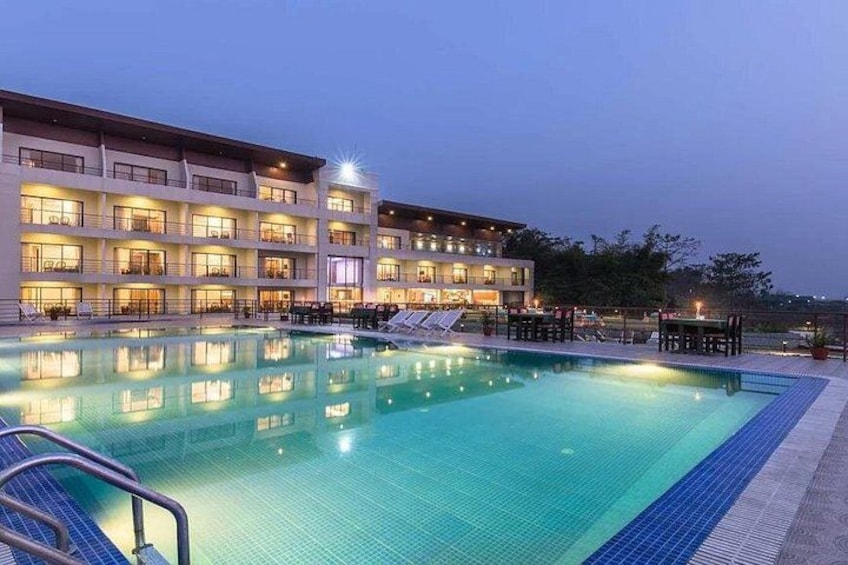 A hotel with a swimming pool, lounge chairs, and a well-lit building facade. 3