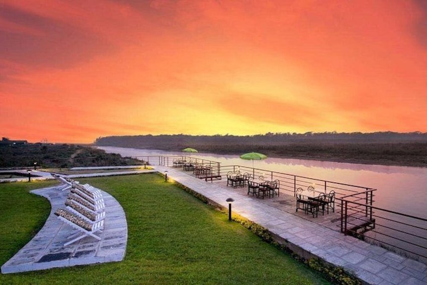 A riverside walkway with seating areas and a grassy embankment. 2