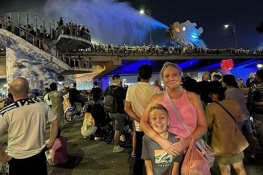 A crowded outdoor event with a large illuminated structure in the background. 3